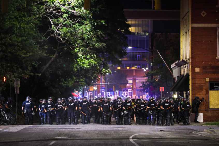CMPD officers stand in line during a demonstration for the end of police brutaity, with The Spectrum Center behind them near uptown Charlotte, North Carolina on June 2, 2020. - US President Donald Trump said June 2, 2020, that he was now looking for a state to host the Republican National Convention later this summer, after  North Carolina said it could not do so as planned due to the coronavirus pandemic. Charlotte was the designated city to hold the Republican convention from August 24 until August 27. (Photo by Logan Cyrus / AFP) (Photo by LOGAN CYRUS/AFP via Getty Images)