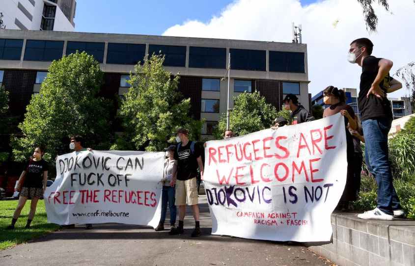 EDITORS NOTE: Graphic content / Pro-refugee activists carry banners outside a government detention centre where Serbia's tennis champion Novak Djokovic is reported to be staying in Melbourne on January 7, 2022, after Australia said it had cancelled the entry visa of Djokovic, opening the way to his detention and deportation in a dramatic reversal for the tennis world number one. (Photo by William WEST / AFP) (Photo by WILLIAM WEST/AFP via Getty Images)