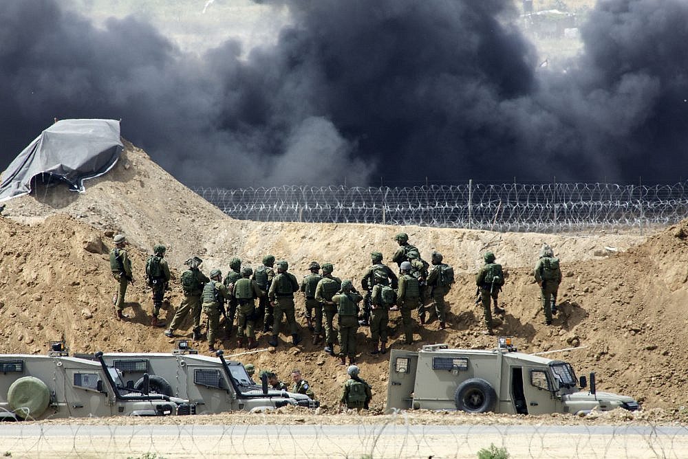 Palestinian protesters demonstrate and burn tires near the Israel-Gaza fence during the Great Return March, April 13, 2018. (Sliman Khader/Flash90)