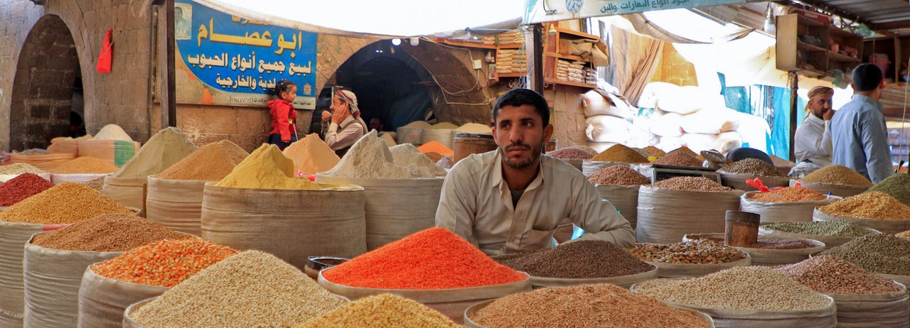 Vendor sells grains at a market in Yemen