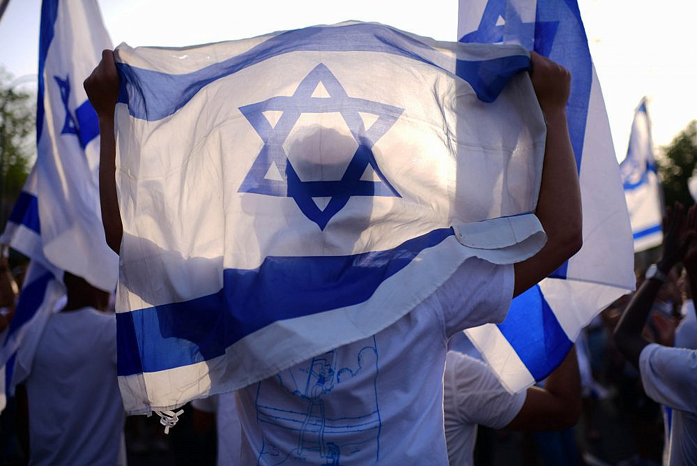 Hundreds of young Jews dance with Israeli flags as they march through the mixed town of Jaffa, in celebration of Jerusalem Day, May 29, 2022. (Tomer Neuberg/Flash90)