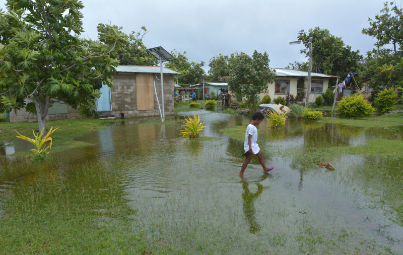 Fijian girl walks over flooded land in Fiji.