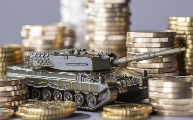 TOY Tank between stacks of coins as a symbol of high Armament expenditure.