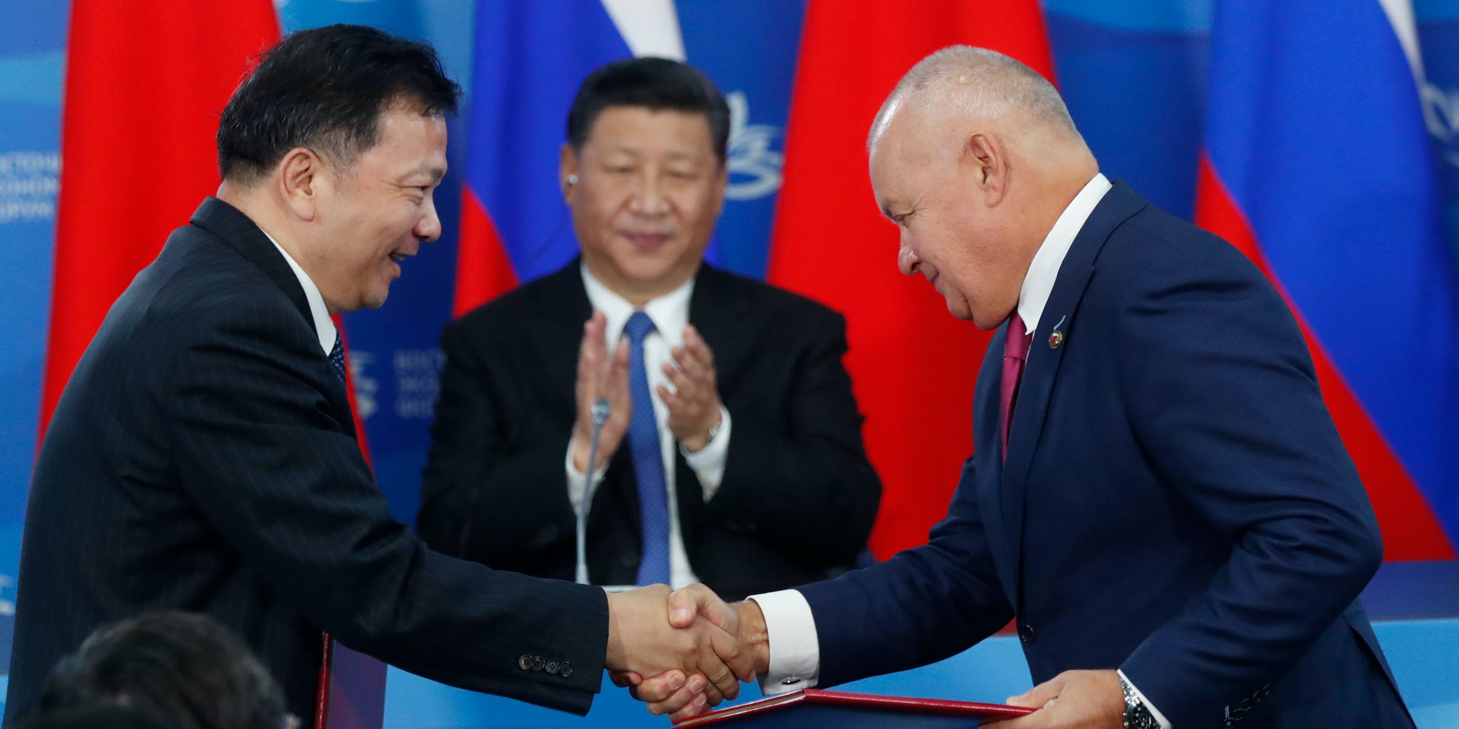 Chinese President Xi Jinping, applauds as Russia's Sputnik news agency head Dmitry Kiselev, right, and head of Chinese Media Corporation Shen Haixiong shake hands, Vladivostok, Russia, Sept. 11, 2018.