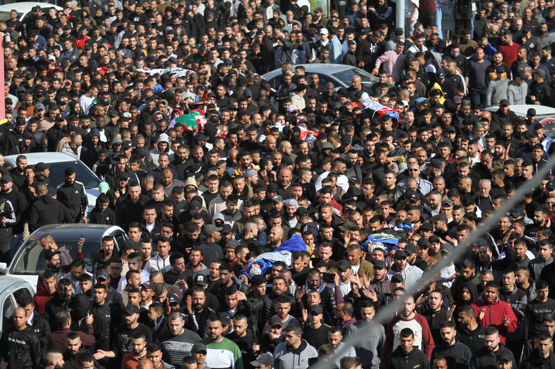 Hundreds of people carry multiple bodies on stretchers 