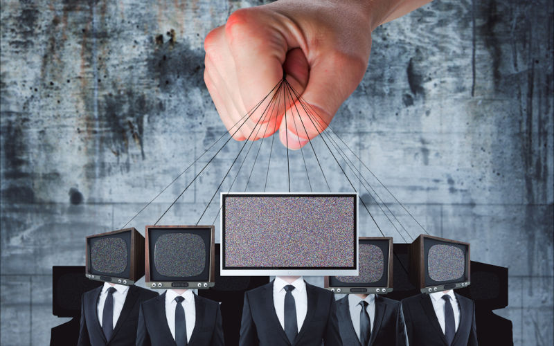 Hand holding TV headed businessmen on rope. Manipulation and brainwash concept.
