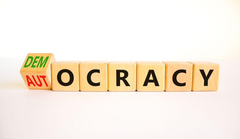 Democracy or autocracy symbol. Turned wooden cubes and changed the concept word Autocracy to Democracy. Beautiful white background. Copy space. Business democracy or autocracy concept.