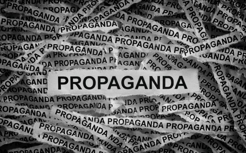 Strips of newspaper with the words Propaganda typed on them. Black and white. Close up.