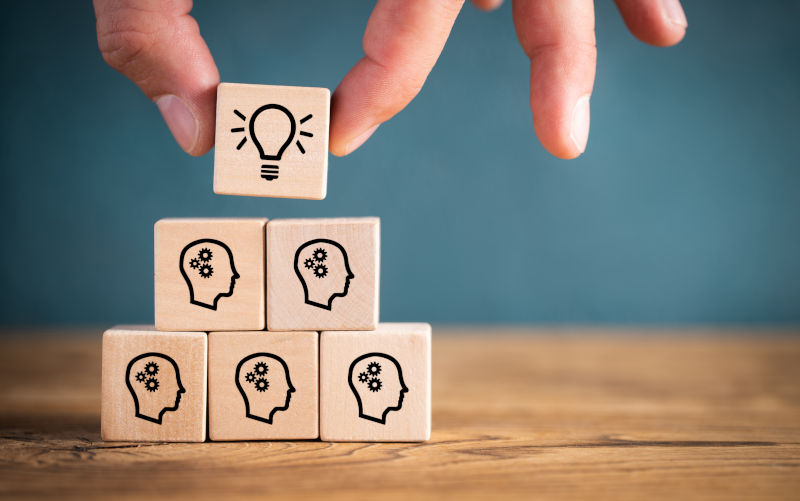 Having-an-idea-symbolised-by-icons-on-cubes. Image: iStock Many people together having an idea symbolised by icons on cubes on wooden background