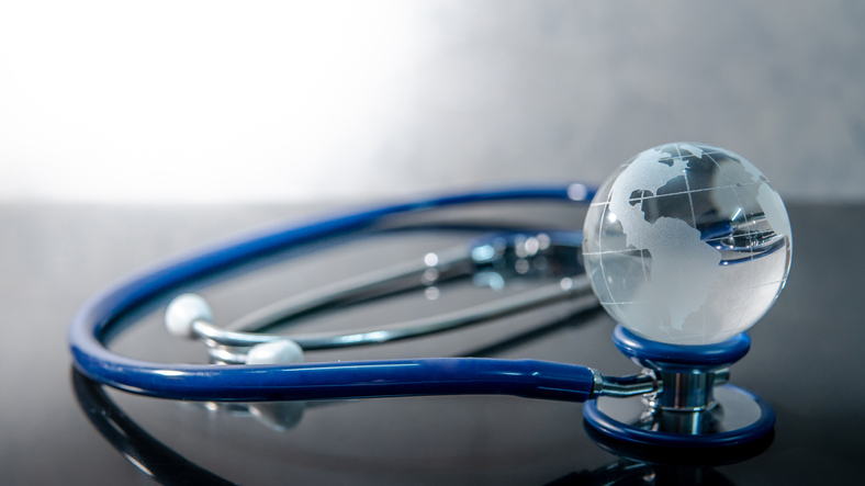 Global healthcare concept. World globe crystal glass on blue stethoscope on glossy desk. Health and medical science. Worldwide wellness business Image: iStock