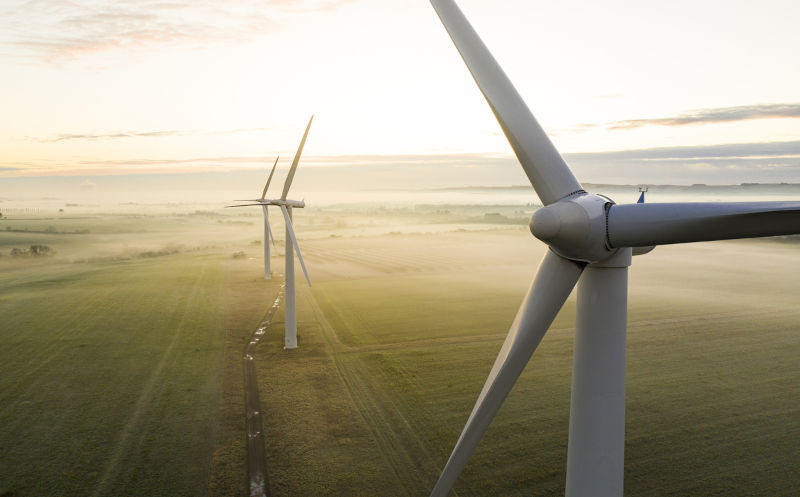 Three-wind-turbines-at-sunrise. Image: iStock / studio-fi Aerial view of three wind turbines in the early morning fog at sunrise.