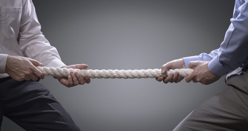 Two businessmen pulling tug of war with a rope concept for business competition, rivalry, challenge or dispute.