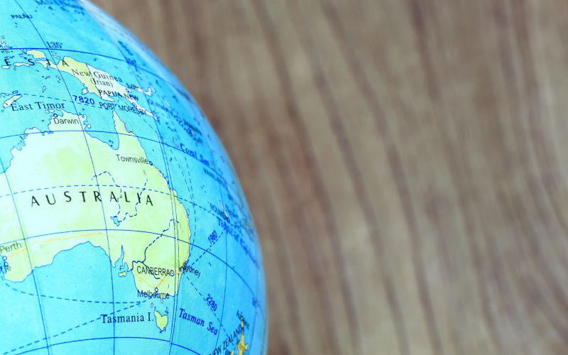 Part of a globe with map of Australia on wood background.