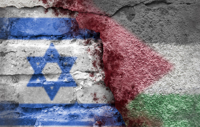 Israeli and Palestinian flags on a brick wall with blood splatters.