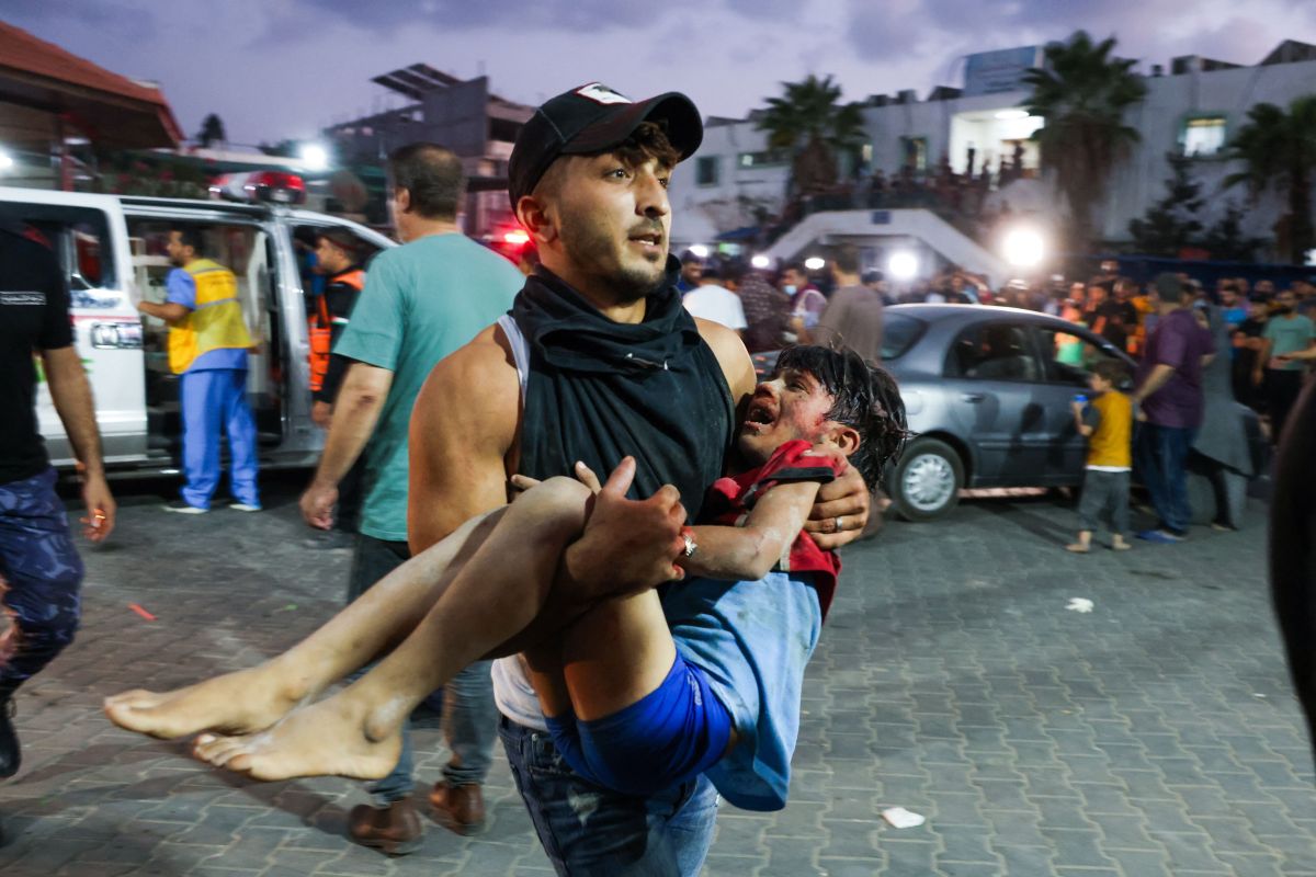 man carries a child, wounded by Israeli airstrikes