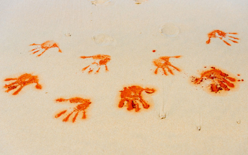 Red soil hand shape on sand in Aboriginal art style,