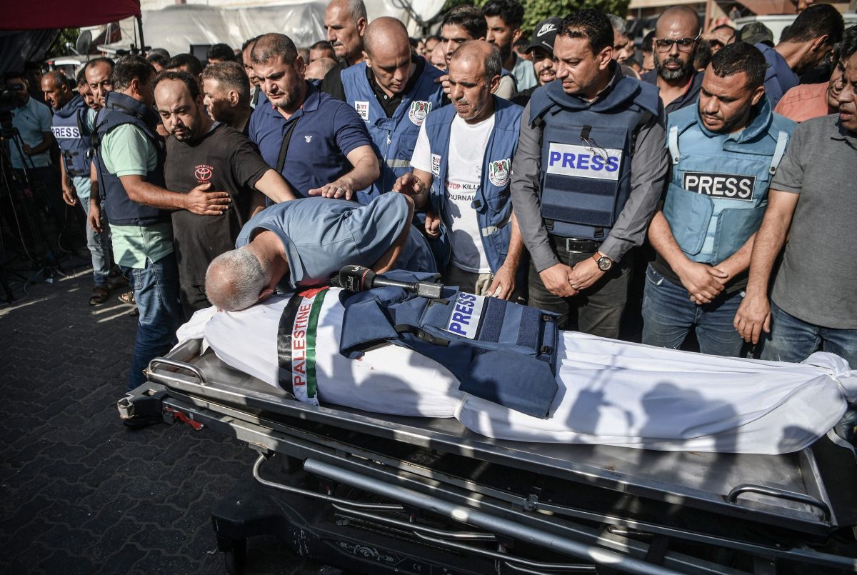 Palestinian journalists in blue "PRESS" flak vests mourn the killing of a colleague by Israeli forces.