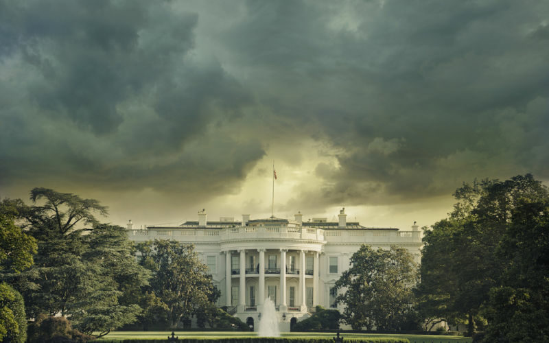 The White House in Washington DC under dark stormy clouds.