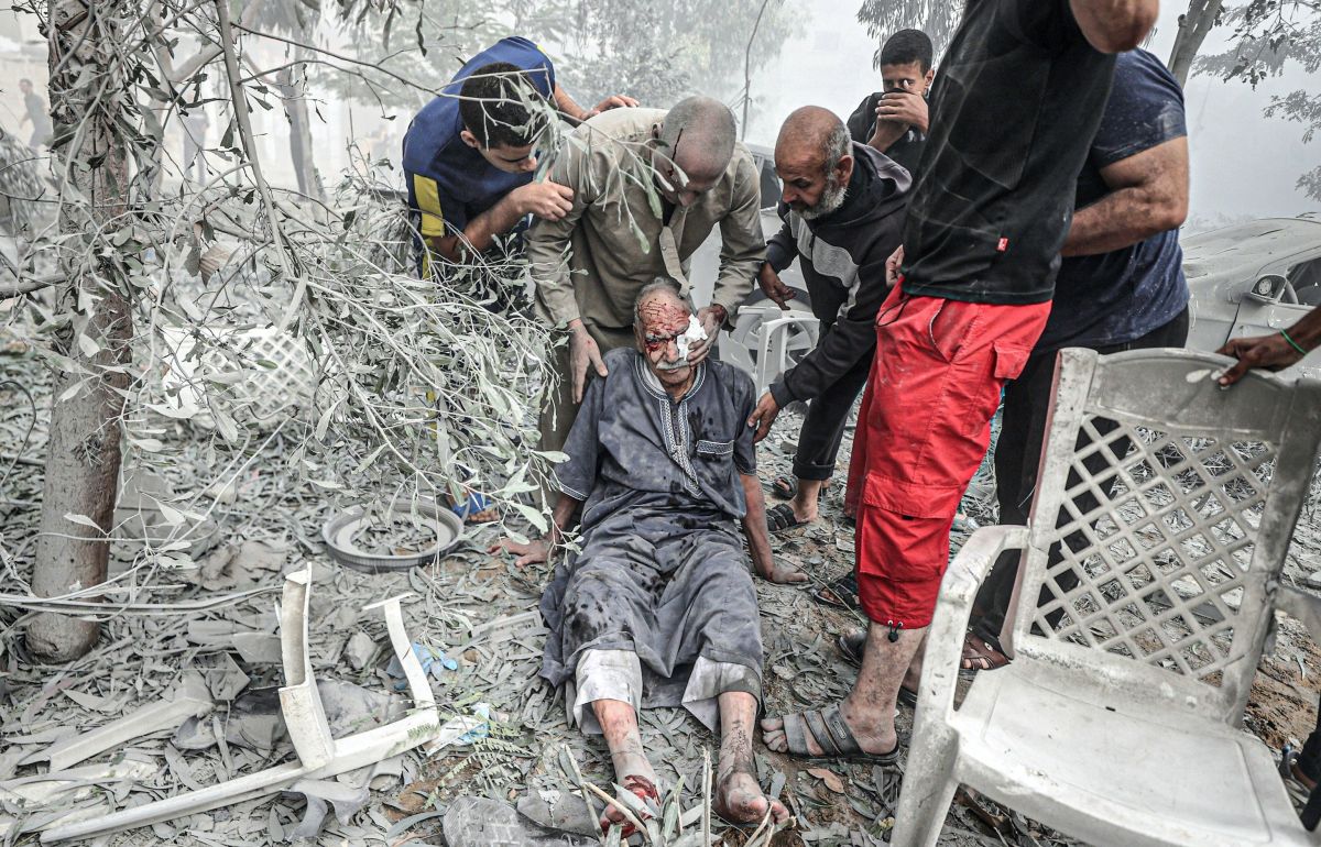 An injured elderly Palestinian man is helped after an Israeli airstrike