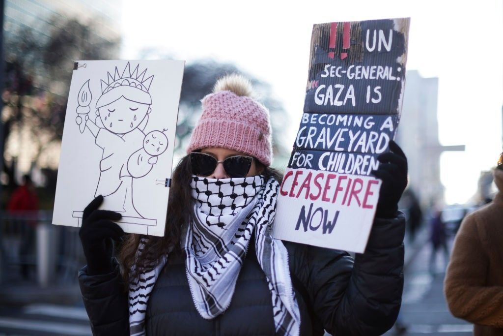 Demonstrator holding picture of Statue of Liberty and sign reading "Ceasefire Now"