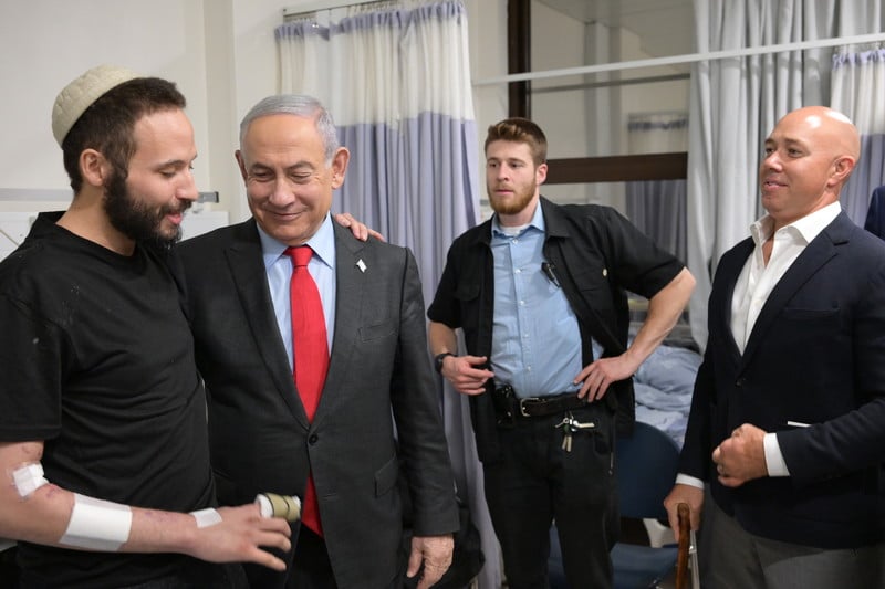 Benjamin Netanyahu and Brian Mast meet with an injured Israeli soldier at a hospital as an additional person looks on