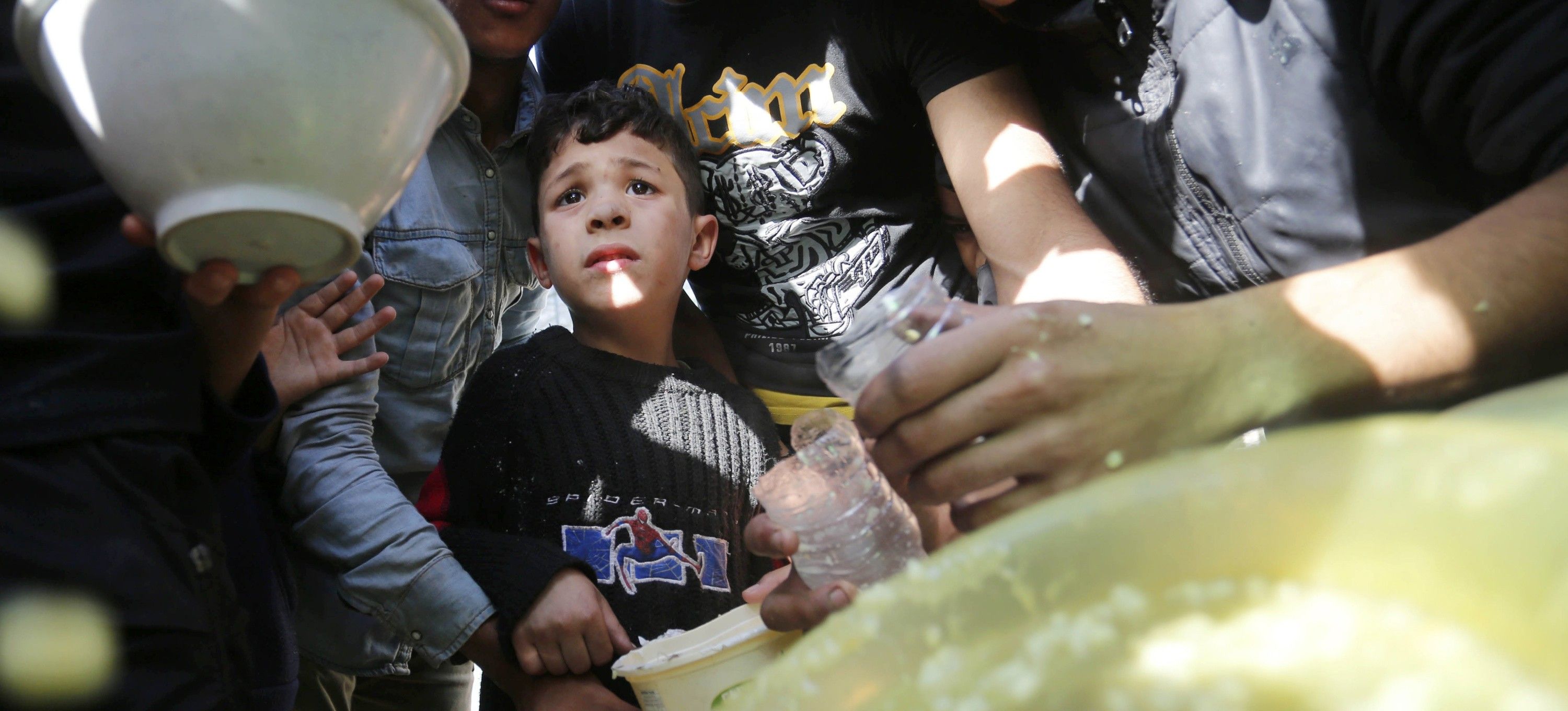 Displaced Palestinians in a tent camp in Deir al Balah wait for soup distributed by volunteers