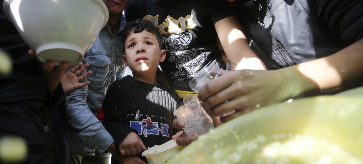 Displaced Palestinians in a tent camp in Deir al Balah wait for soup distributed by volunteers