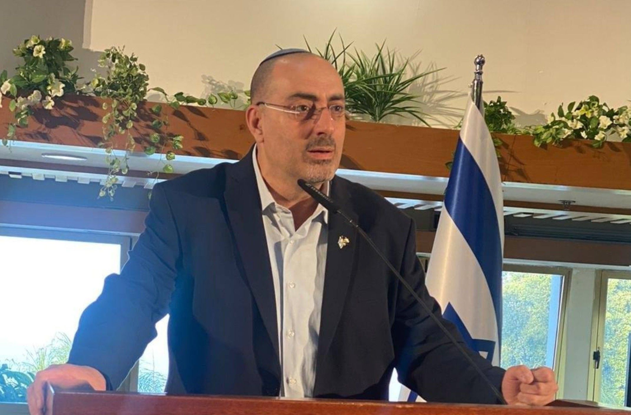 Israeli Deputy Knesset Speaker Nissim Vaturi delivers a speech beside an Israeli flag