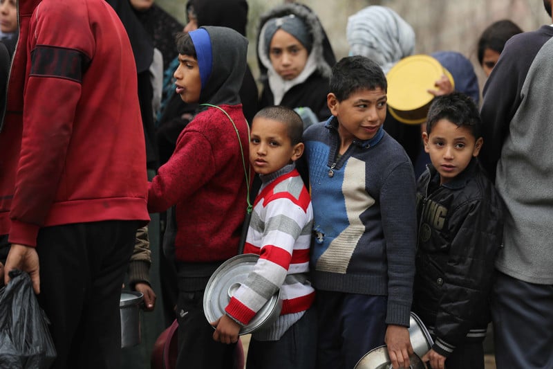 A crowd of children holding metal food containers.