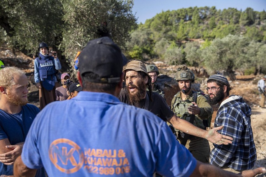 Armed Israeli settlers harass Palestinian farmers and activists from the Faz3a campaign during olive harvest in the village of Jibya, West Bank, October 28, 2022. (Anne Paq/Activestills)