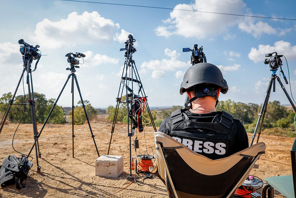 Foreign and Israeli journalists stand on a hill overlooking the Gaza Strip in the city of Sderot, southern Israel, October 19, 2023. (Nati Shohat/Flash90)