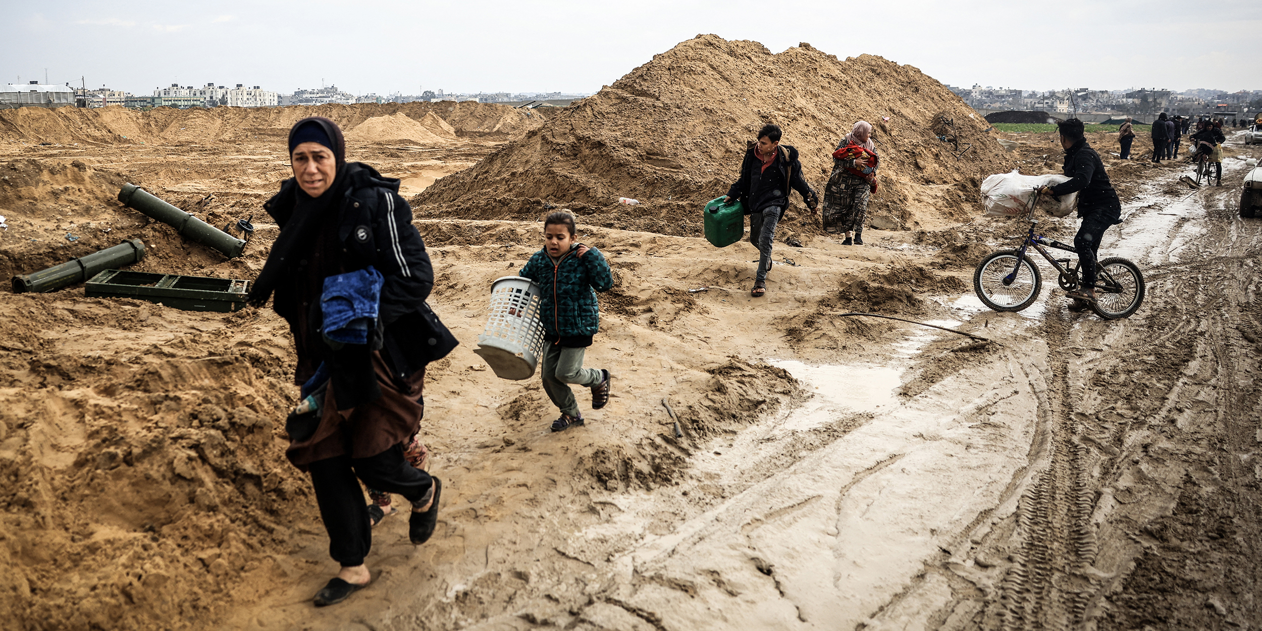 Palestinians carrying some belongings walk past ammunition containers left behind by Israeli troops as they flee Khan Yunis in the southern Gaza Strip further south on February 2, 2024, amid ongoing battles between Israel and the militant group Hamas. (Photo by Mahmud Hams / AFP) (Photo by MAHMUD HAMS/AFP via Getty Images)