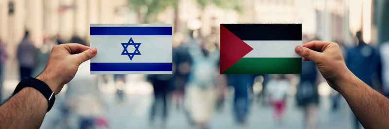 Palestine-Israel-culture,-religion-and-territory.-Diplomacy-and-future-strategy,-relations. Image: iStock / Bulat Silvia Hands holding Palestine vs Israel flags as dispute on politics, culture, religion and territory. Diplomacy and future strategy, relations between countries. Cooperation or opposite conflict concept.