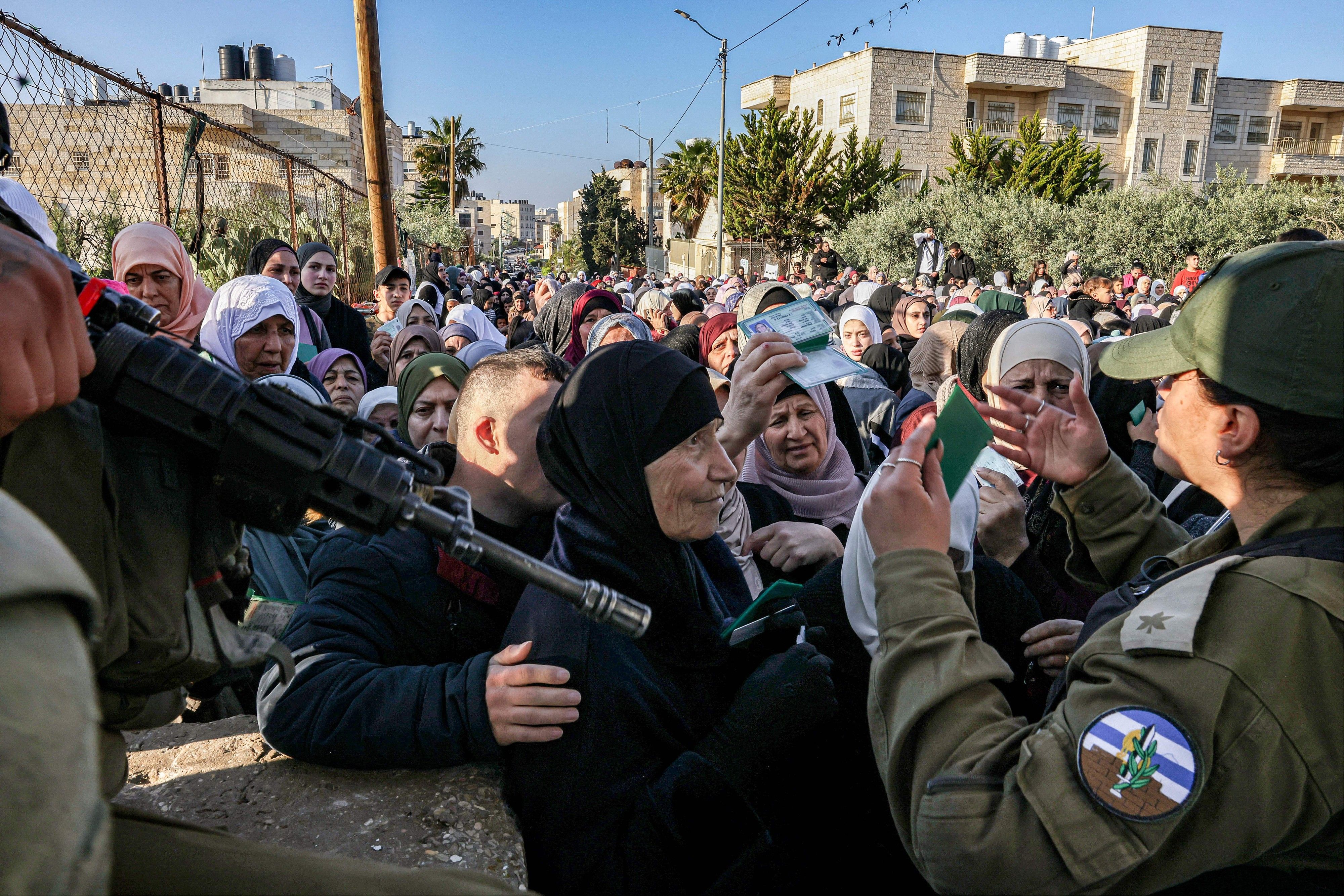 Israeli troops control a large group of Palestinian woman at gunpoint