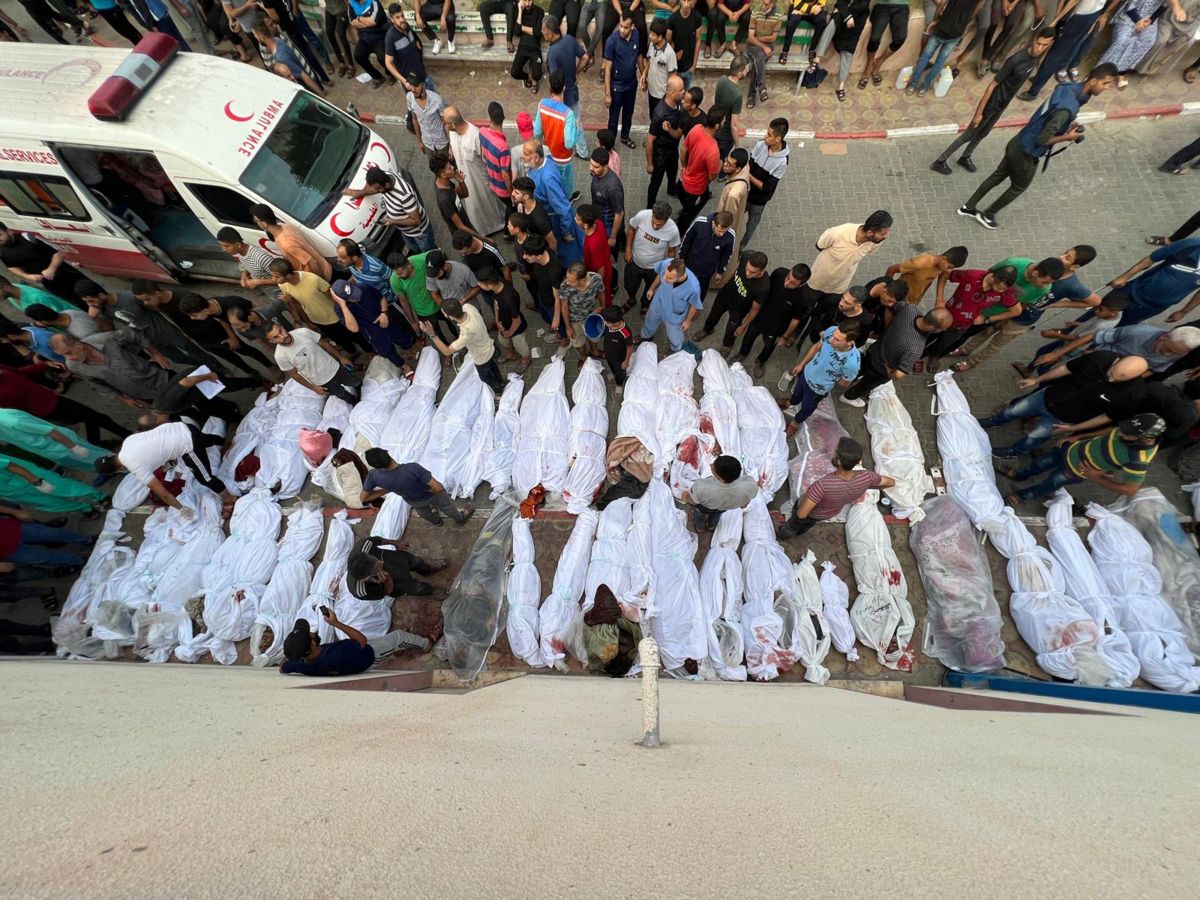 Dozens of Palestinian bodies wrapped in white sheets are lined up in the street