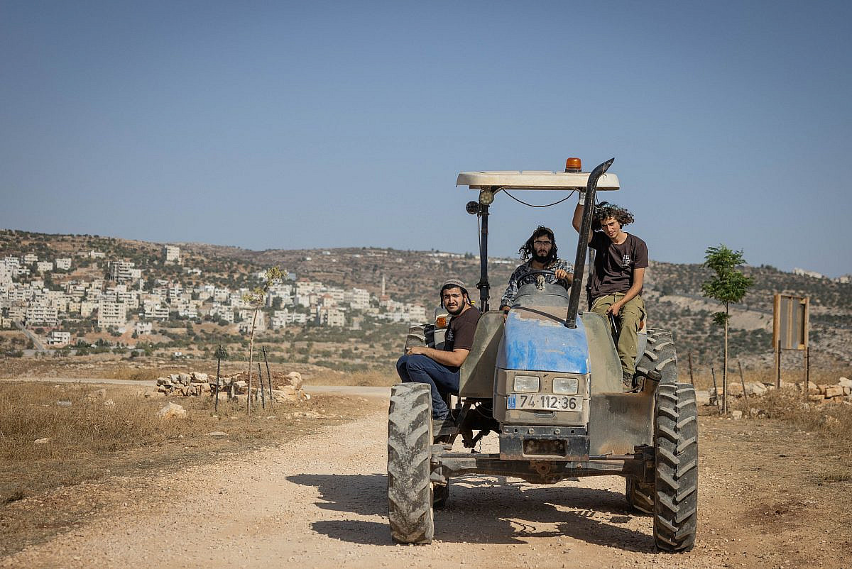 Israeli settlers drive a tractor in the outpost of Ramat Migron, occupied West Bank, September 8, 2023. (Chaim Goldberg/Flash90) Israeli settlers drive a tractor in the outpost of Ramat Migron, occupied West Bank, September 8, 2023. (Chaim Goldberg/Flash90)