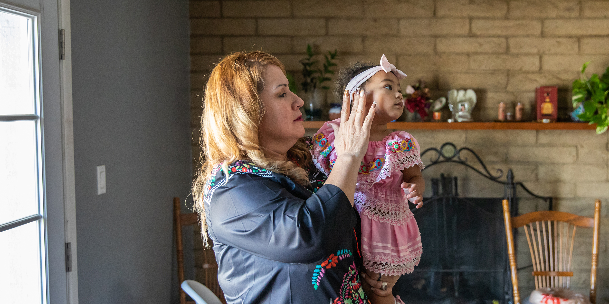 Martha Rodriguez comforts her 14-month-old granddaughter MD on October 20, 2023 at home in Phoenix, AZ. Childcare has become too expensive for her family so Rodriguez steps in after her early morning shift at an industrial laundry while her daughter works.