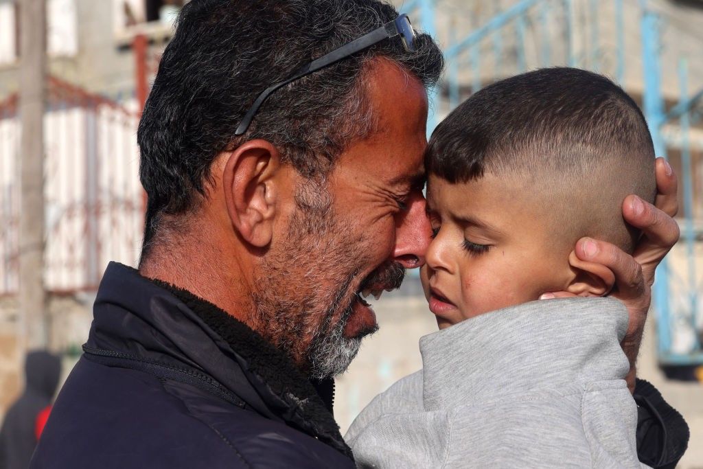 Palestinian man cries as he holds a child
