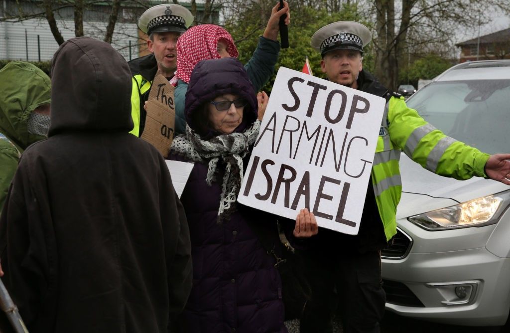 Person holding sign "Stop Arming Israel"