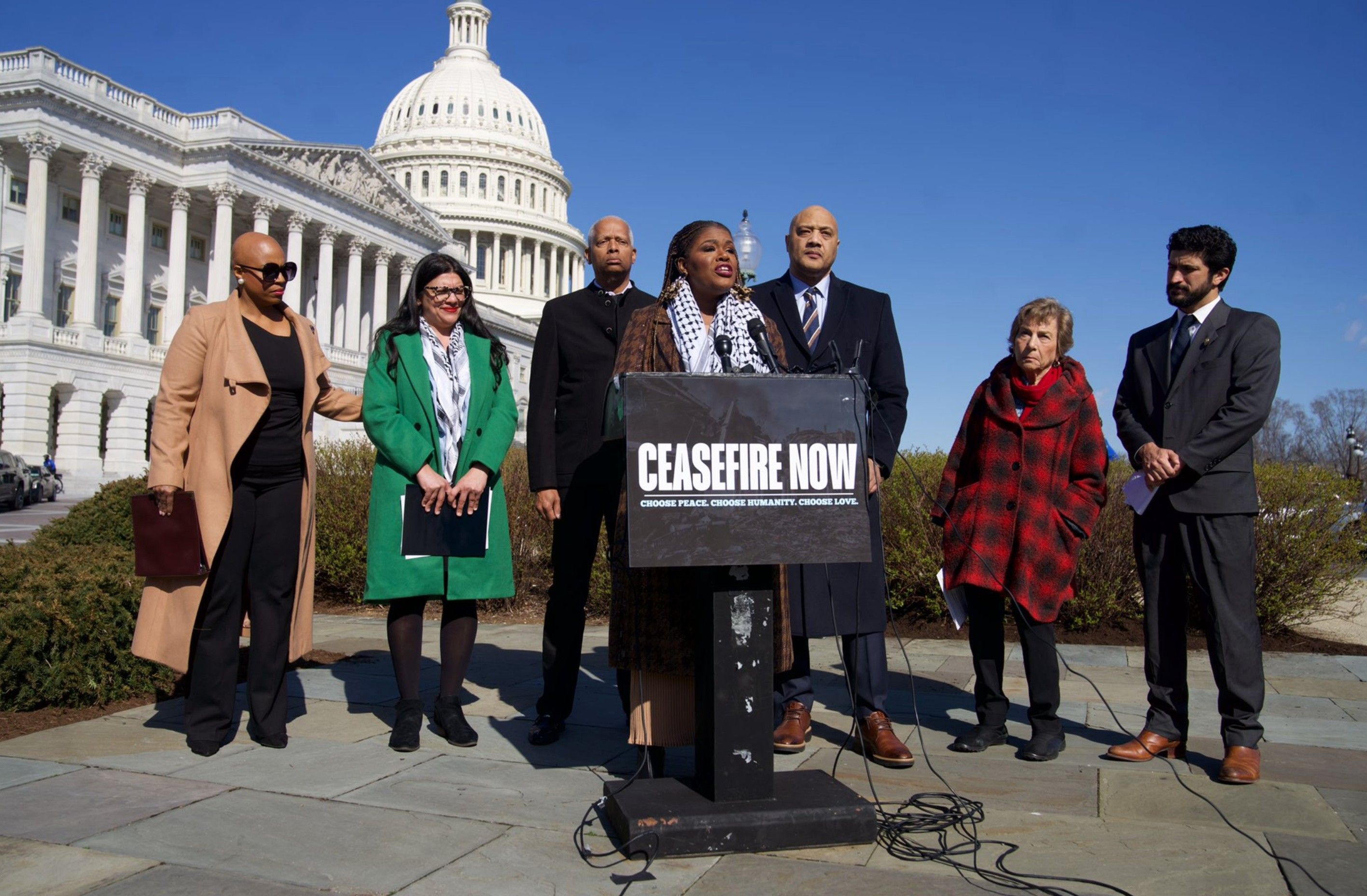 Rep. Cori Bush speaks outside the U.S. Capitol with a "cease-fire now" sign on the podium.