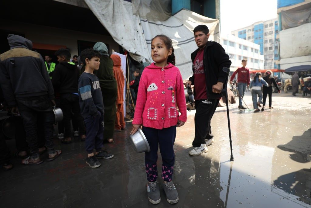 A child waits with an empty pot 
