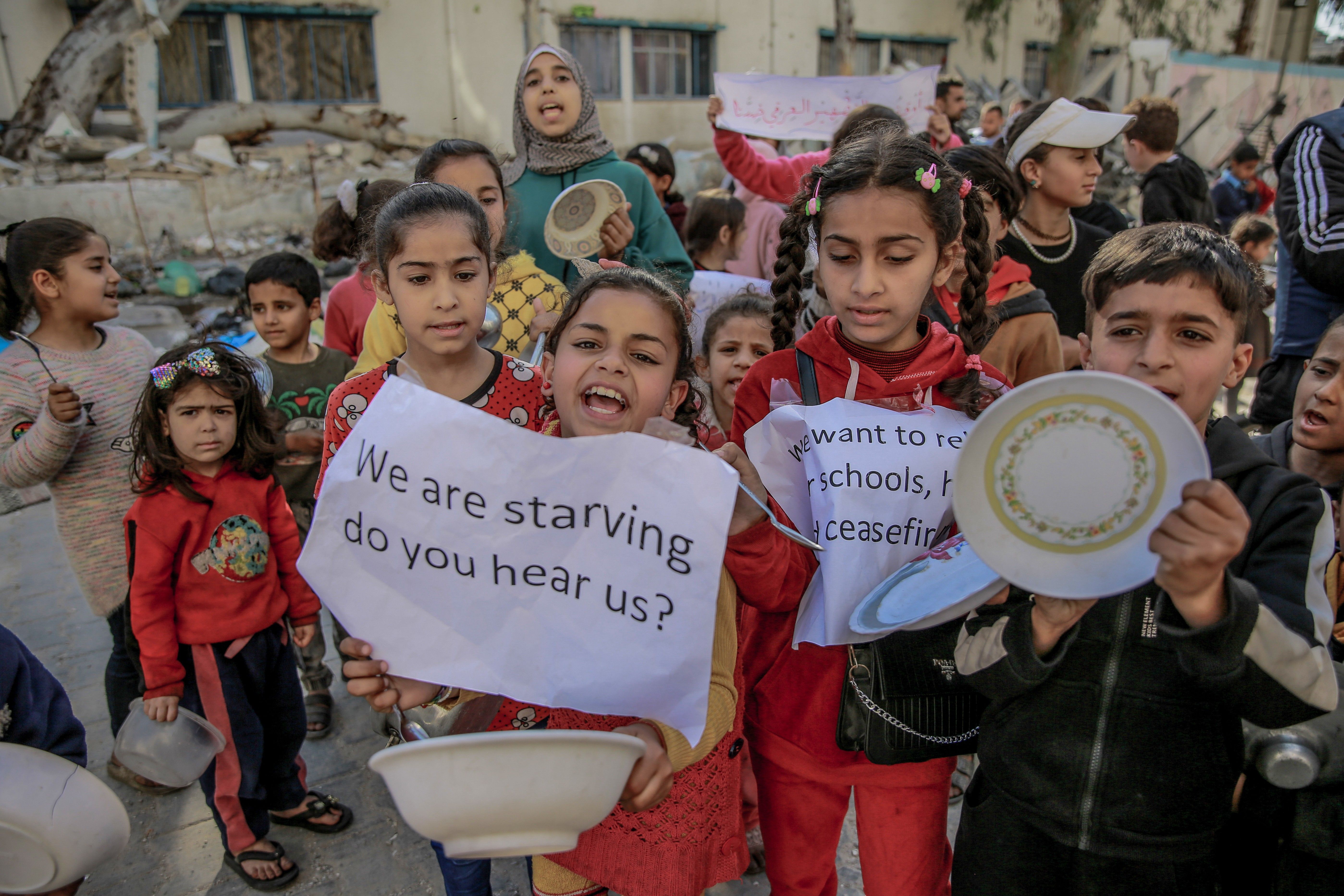 Palestinian children holding banners and empty bowl