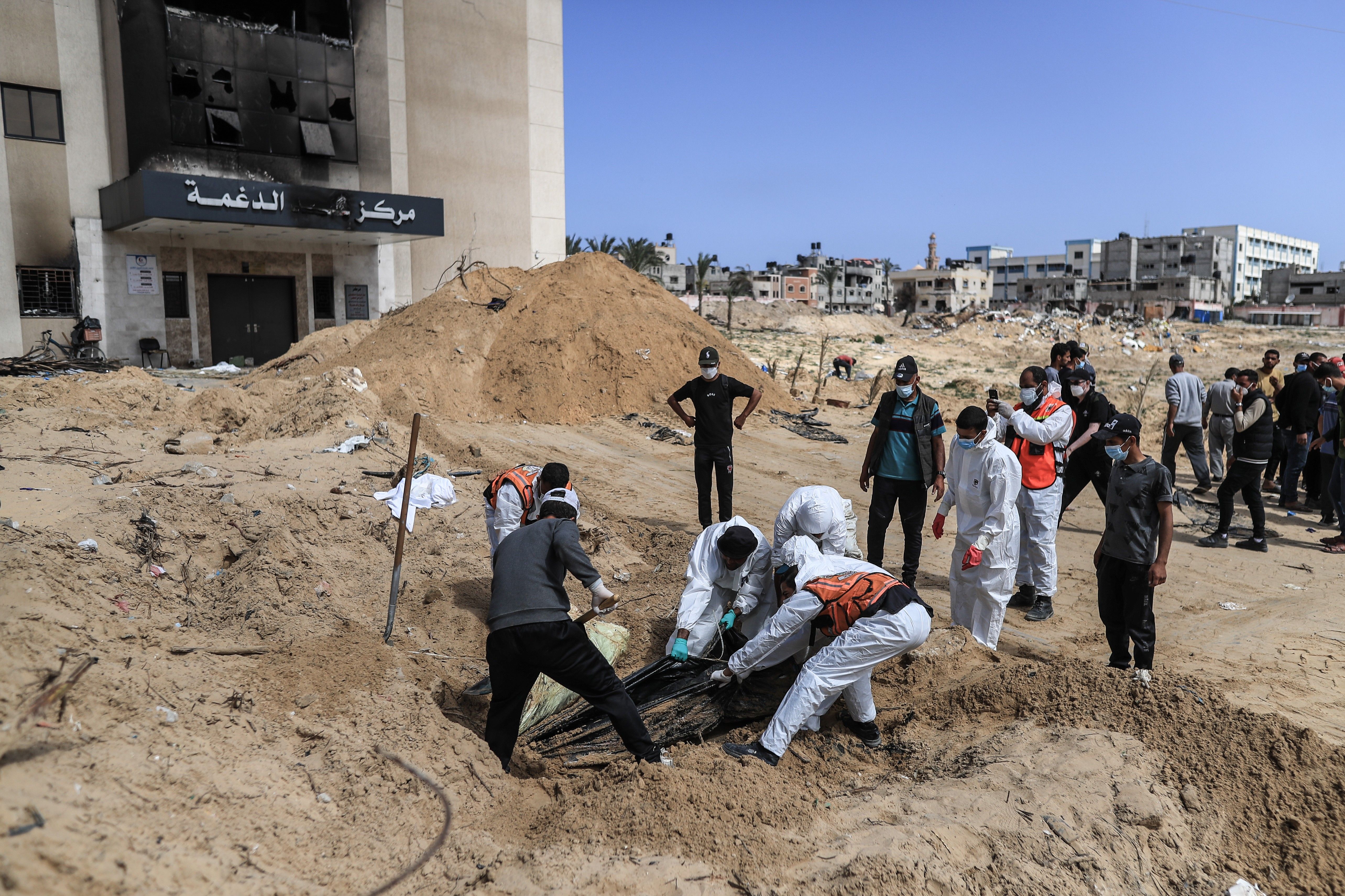 Palestinian civil defense workers remove bodies from rubble in Khan Younis.