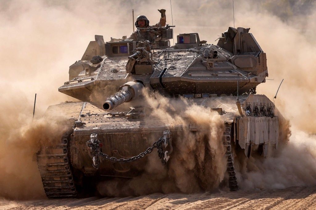 An Israeli army soldier gestures as he rides atop a main battle tank