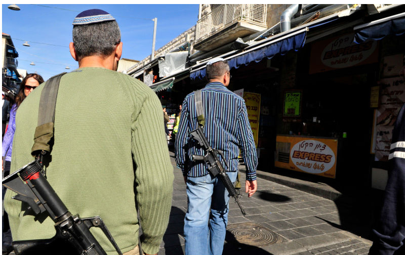 Jewish settlers with their rifles at the vibrant Machane Yehuda market in Jerusalem, Israel. December 2009