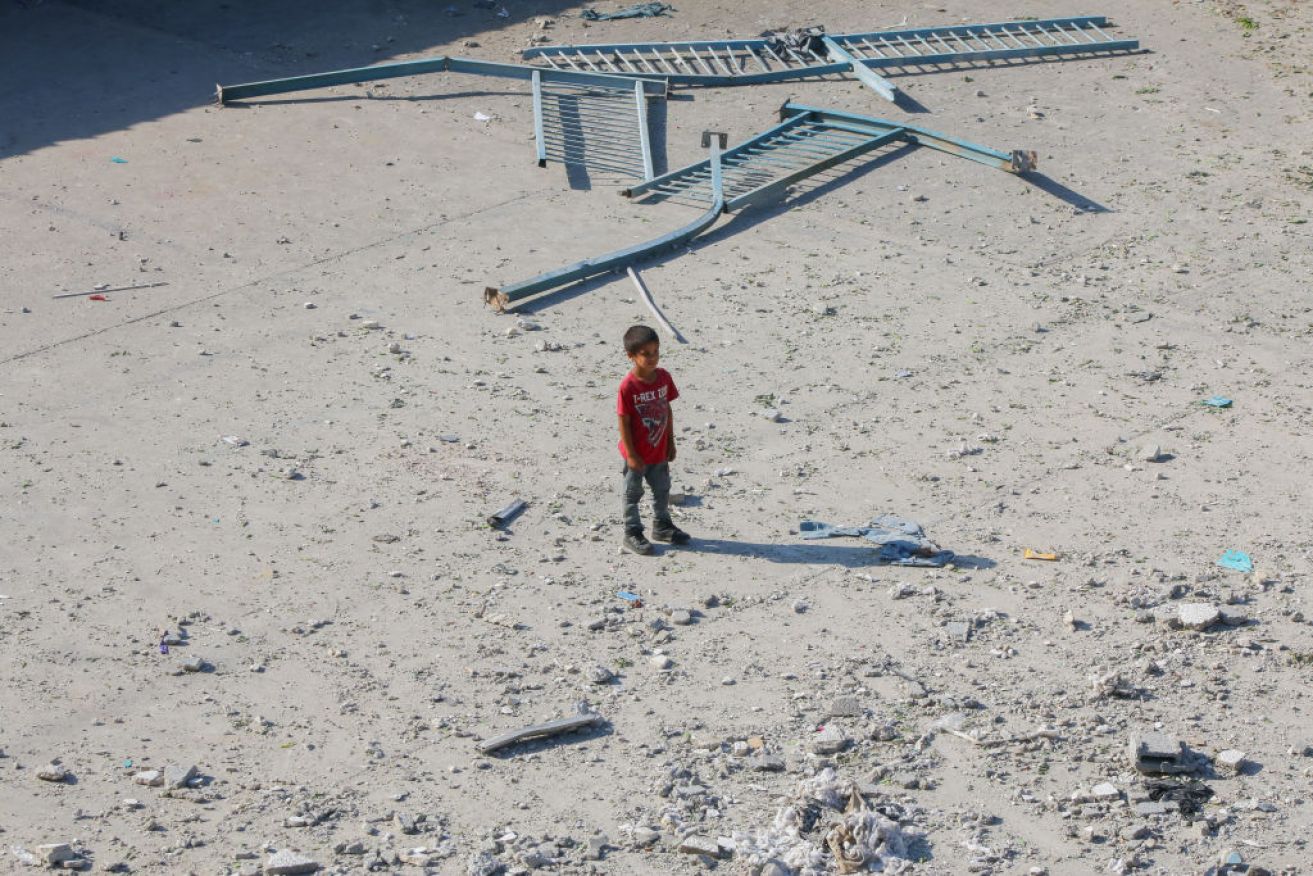 A Palestinian boy stands among rubble from a UN-run school that was housing displaced people in Nuseirat, in the central Gaza Strip, and was hit during an Israeli bombardment.
