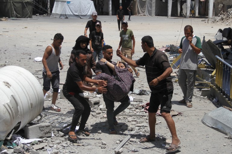 Palestinians carry a wounded outside the UNRWA headquarters following an Israeli attack in Gaza City,