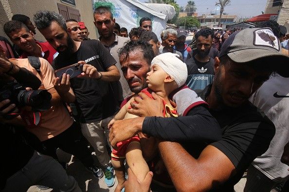 A Palestinian man carries a child to receive medical treatment 